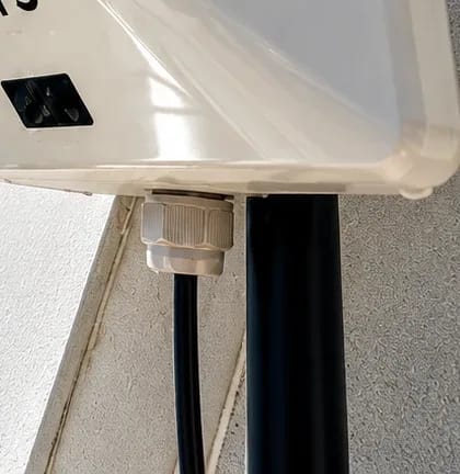 Cabo de rede saindo do conector vedado na base do modem 5G